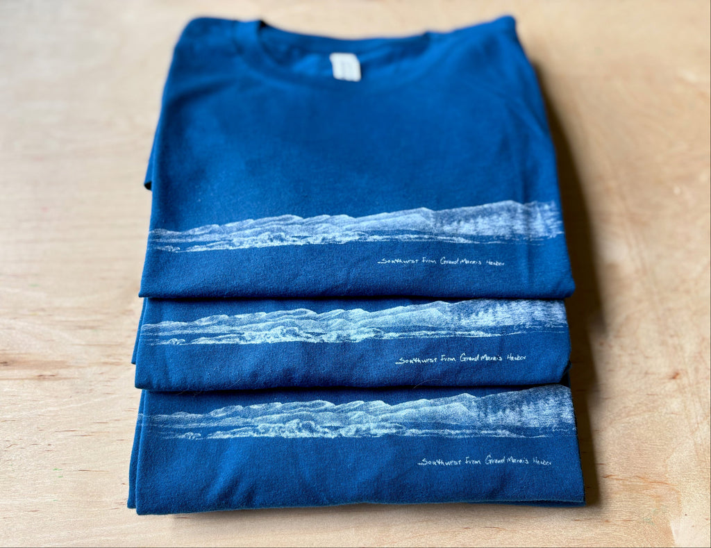 Folded blue t-shirt with white graphic design on a wooden surface
