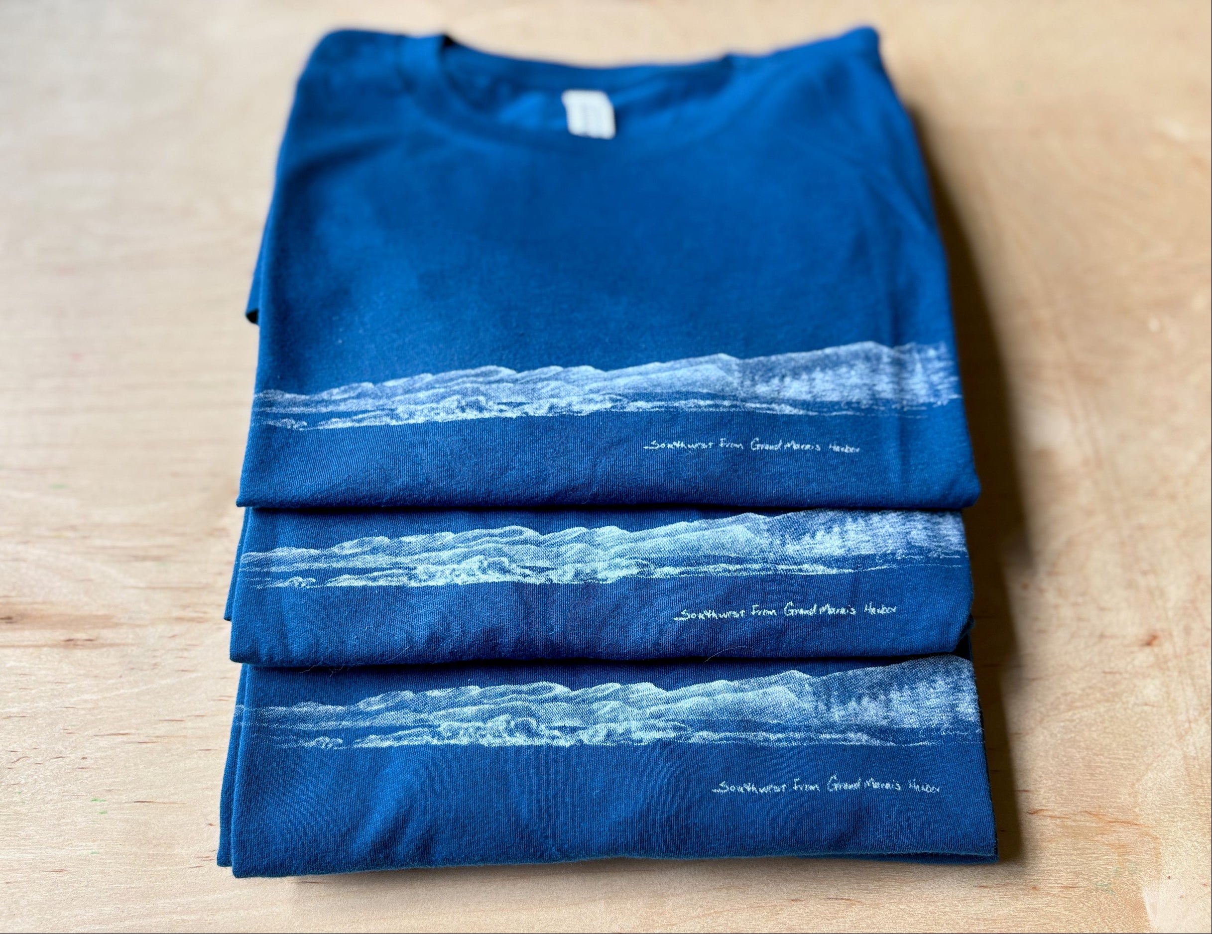 Folded blue t-shirt with white graphic design on a wooden surface